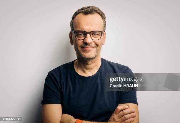 lächelnder mann mit gekreuzten armen mit brille - blue studio stock-fotos und bilder