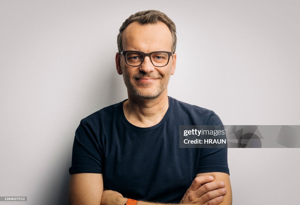 Hombre sonriente con los brazos cruzados usando anteojos