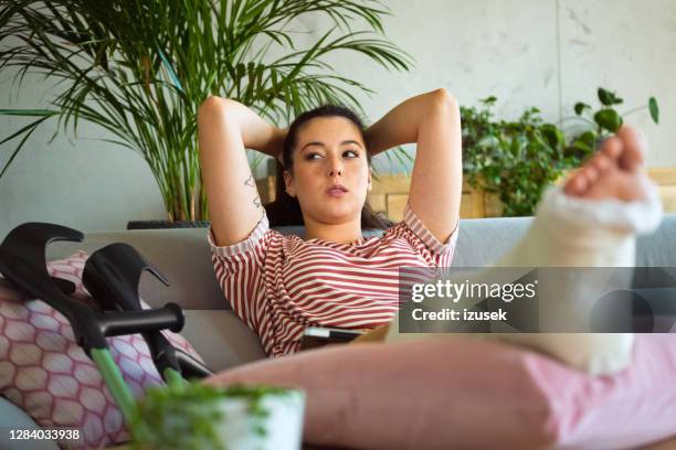 einsame junge frau mit gebrochenem bein zu hause - knochenbruch stock-fotos und bilder