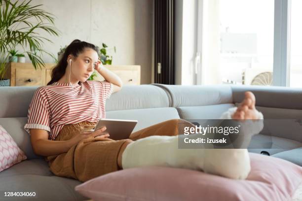 sad young woman with broken leg at home - broken leg stock pictures, royalty-free photos & images