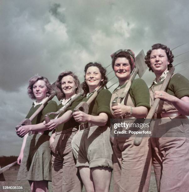 Five Land Girls from the Women's Land Army line up with forks and spades at their hostel in the village of Risby, Suffolk prior to starting work on a...