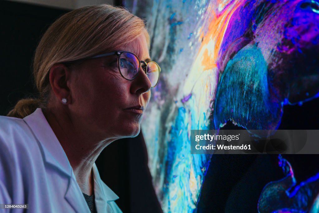 Female scientist studying about human brain with nerve fiber while standing at laboratory