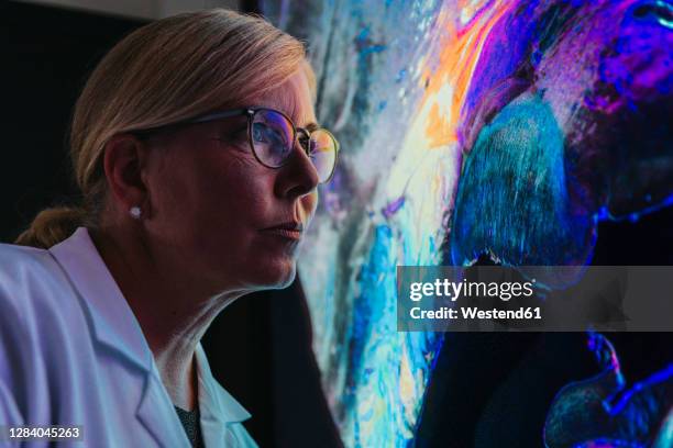 female scientist studying about human brain with nerve fiber while standing at laboratory - abstract science stockfoto's en -beelden