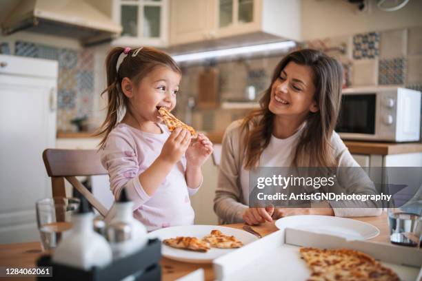 madre e hija comiendo pizza en casa. - comida no saludable fotografías e imágenes de stock