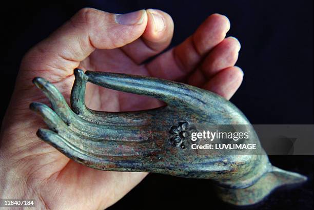 two mudras, bronze buddha hand held by male hand - buddha hands stock-fotos und bilder