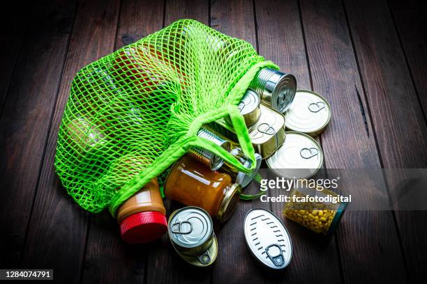 alimentos no perecederos que salen de una bolsa de compras reutilizable verde. copiar espacio - estaño fotografías e imágenes de stock