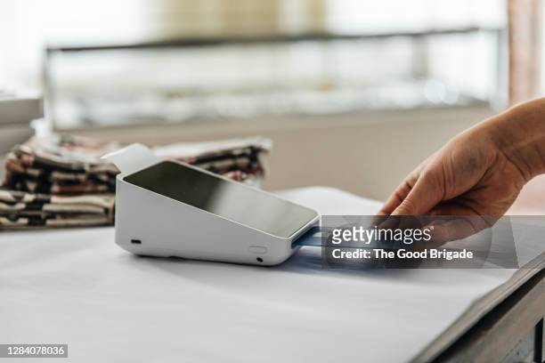 close up of woman making contactless payment in store - kreditkartenlesegerät stock-fotos und bilder