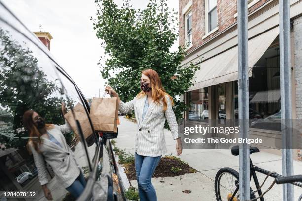 shop owner delivering purchase to customer in car - カーブサイドピックアップ ストックフォトと画像