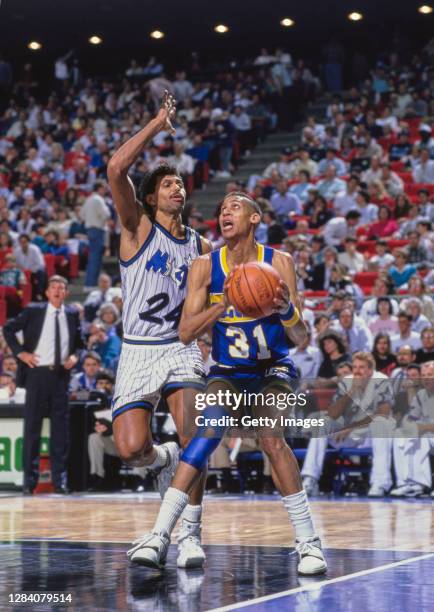 Reggie Miller, Shooting Guard for the Indiana Pacers prepares to shoot as Point Guard Reggie Theus of the Orlando Magic attempts to block during...