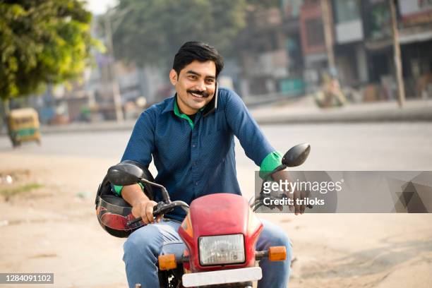 man riding motorcycle and talking on mobile phone - sports helmet stock pictures, royalty-free photos & images