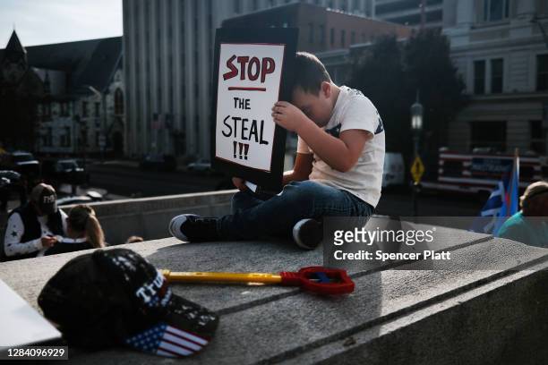 Child holds a sign as dozens of people calling for stopping the vote count in Pennsylvania due to alleged fraud against President Donald Trump gather...
