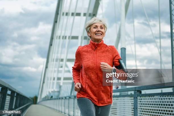 smiling mature woman running - active senior woman imagens e fotografias de stock