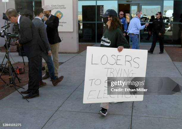 Woman holds a "Losers Trying To Steal Election" sign outside the Clark County Election Department, where ballots from the election are being counted,...