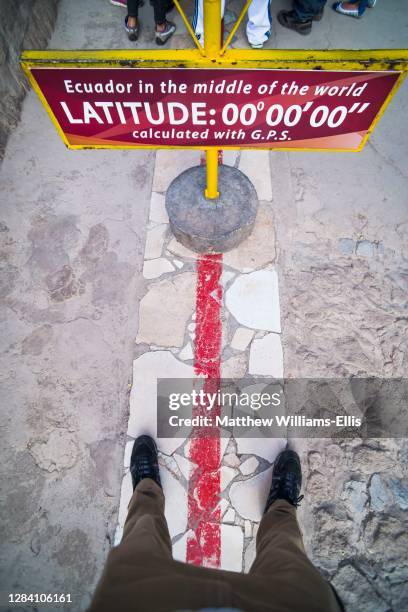 One foot in the northern and southern hemisphere at the Equator at 'Middle of the World', San Antonio de Pichincha, Quito, Ecuador, South America.