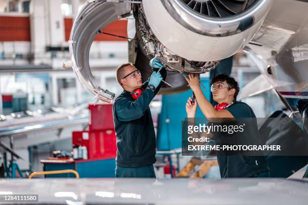 junge flugzeugmechaniker arbeiten an einem düsentriebwerk im hangar - aviation hat stock-fotos und bilder
