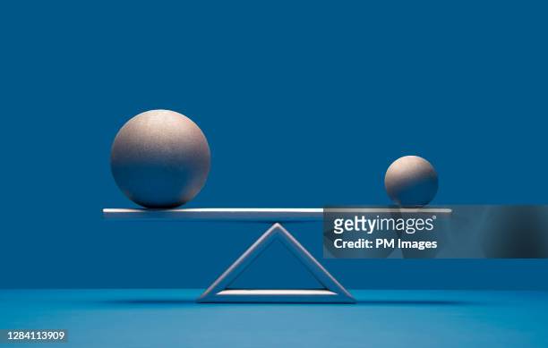 balls balancing on scale - compare size stockfoto's en -beelden