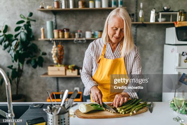 seniorin schneidet gemüse in der küche - asparagus stock-fotos und bilder