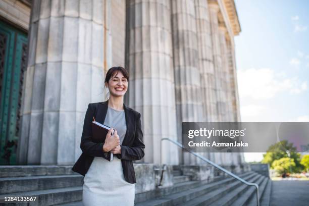 smiling hispanic female law student carrying book - law student stock pictures, royalty-free photos & images