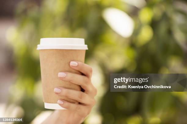mockup of male hand holding a coffee paper cup isolated on light grey background. - disposable cup foto e immagini stock