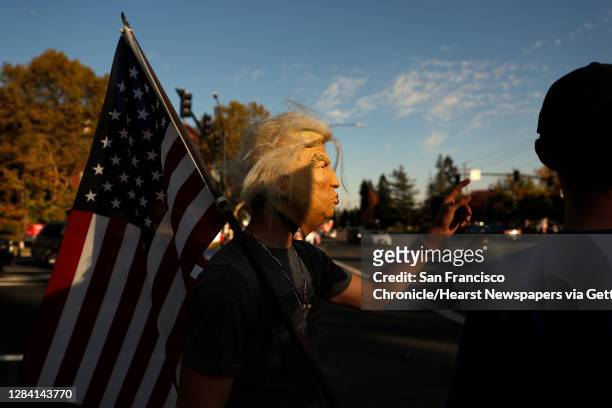 Young man, who didn't want to be identified, wears a Donald Trump mask while doing supporters of US president Donald Trump taking part in a "Trump...