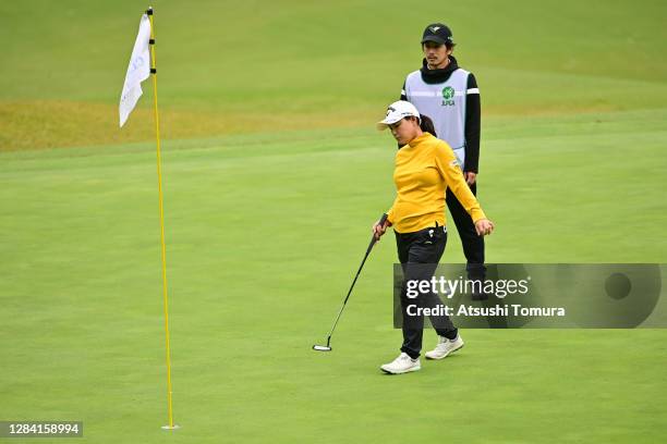 Sakura Yokomine of Japan, who is 7-month pregnant, lines up a putt with her caddie and husband Yotaro Morikawa on the 17th green during the first...