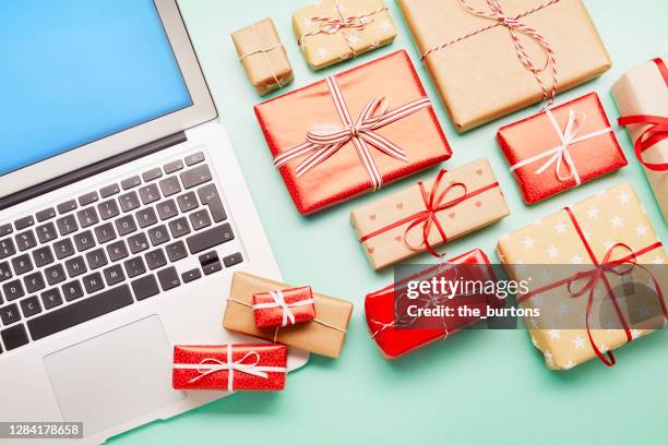 high angle view of a laptop computer and gifts on turquoise background, online shopping - retail economy ahead of christmas holiday season imagens e fotografias de stock