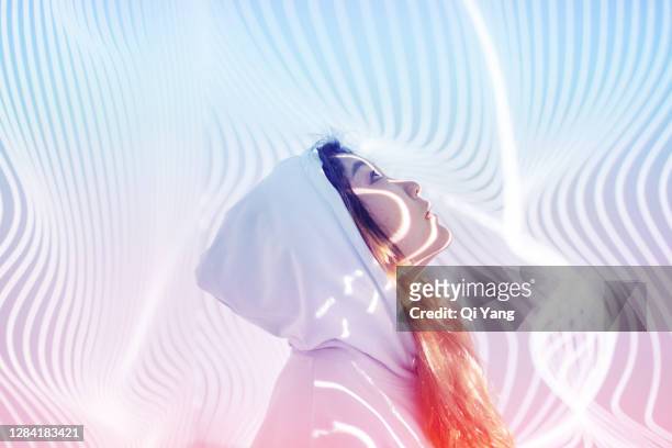 young woman standing in holographic background - kreativität stock-fotos und bilder