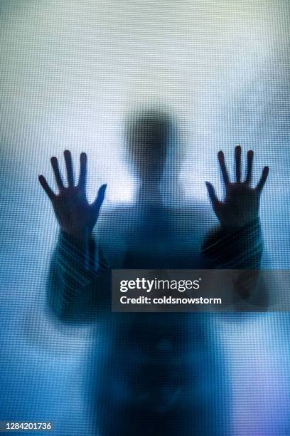 silhouet van gedeprimeerde misbruikte vrouw met handen die tegen glas worden gedrukt - ontsnapping uit de gevangenis stockfoto's en -beelden