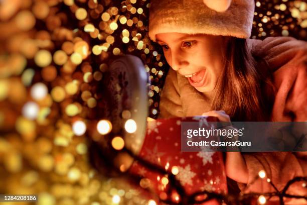 aufgeregtes kleines mädchen, das ihr weihnachtsgeschenk in der nacht anschaut - gift lounge stock-fotos und bilder