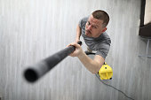 A man collects dust with hose from vacuum cleaner