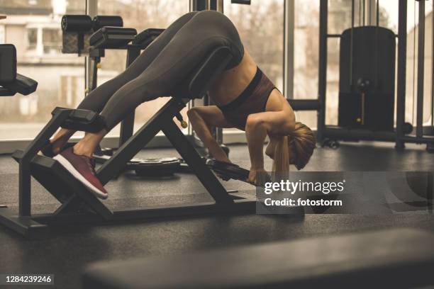 woman working out her lower back on a back extension machine - lower back stock pictures, royalty-free photos & images