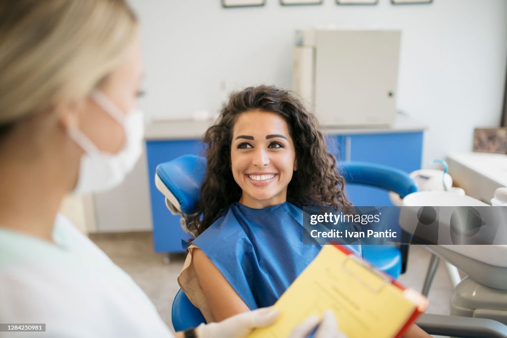 Attractive young Caucasian woman talking to her dentist