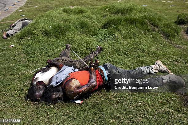 The bodies of two executed Gaddafi loyalist soldiers, their hands bound, lie on a grassy roundabout outside the south entrance of the Bab al-Aziziyia...