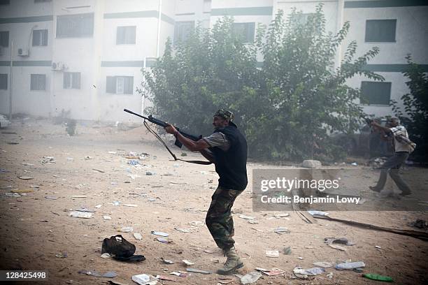 Libyan rebels fire their AK-47s at a building housing a Gaddafi loyalist sniper in the dangerous Abu Salim neighborhood on August 25 2011 in Tripoli,...