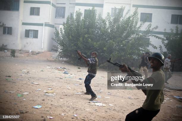 Libyan rebels fire their AK-47s at a building housing a Gaddafi loyalist sniper in the dangerous Abu Salim neighborhood on August 25 2011 in Tripoli,...