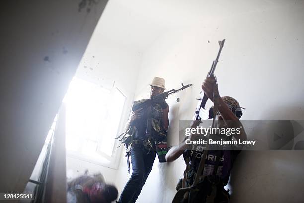 As his comrades flee, a Libyan rebel soldier falls after being shot in the head and killed by a Gaddafi loyalist sniper hiding out on the floor above...