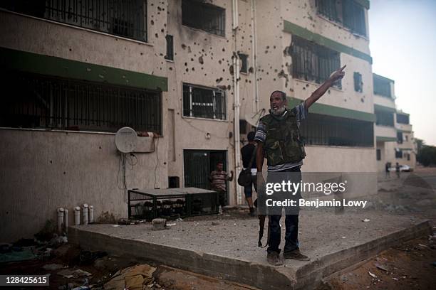 Libyan rebel screams for rooftop fighters to fire on a building housing a Gaddafi loyalist sniper in the dangerous Abu Salim neighborhood on August...