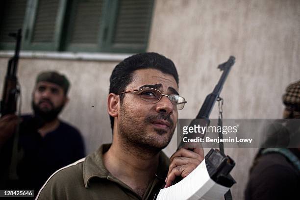 Libyan rebels missing one lens from his glasses, watches as rebel snipers fire their weapons at a building housing a Gaddafi loyalist sniper in the...