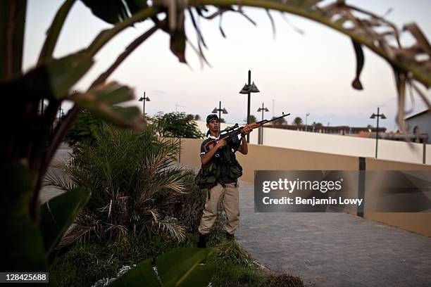 Rebel sniper aims his weapon at a suspected Gaddafi loyalist sniper who targeted the Corninthian hotel, home to a large cadre of international...