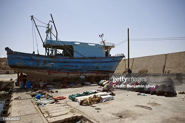 Internally displaced African migrant workers pray towards Mecca while living in misreable conditions in a deserted dry dock port filled with the...
