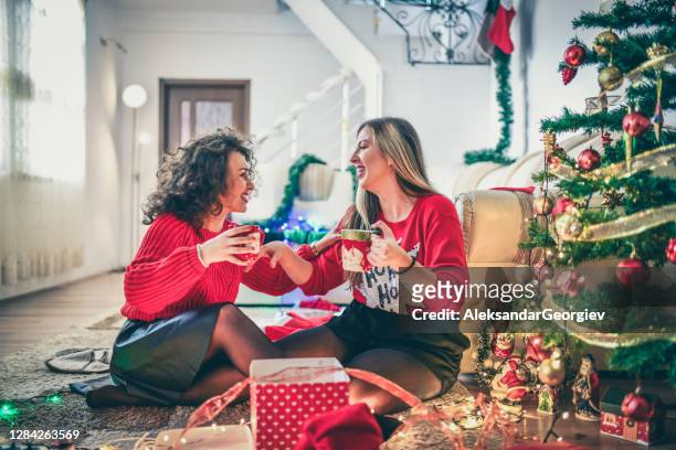 lesbian couple opening christmas gifts together under the tree - gay santa claus stock pictures, royalty-free photos & images
