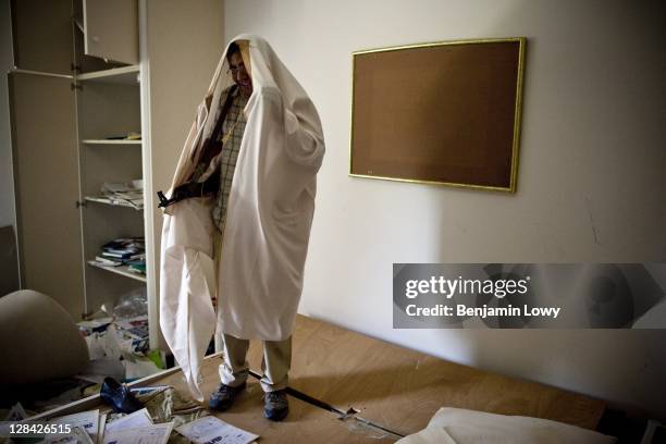 Libyan rebels dresses in one of Gaddafi's robes while walking through the looted and NATO bombed home of former Libyan dictator Moammar Gaddafi's son...