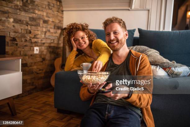 young couple watching a movie at home. - watching stock pictures, royalty-free photos & images