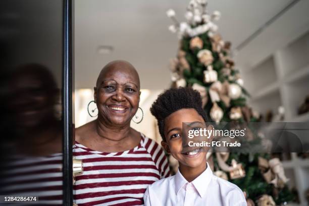 portret van grootmoeder en kleinzoon die zich in de deuropening voor kerstmis bevinden - homeowners decorate their houses for christmas stockfoto's en -beelden