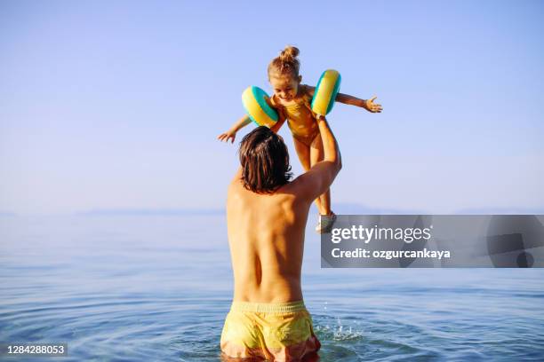 handsome father jumping with his daughter in sea - young girl jumping into swimming pool stock pictures, royalty-free photos & images