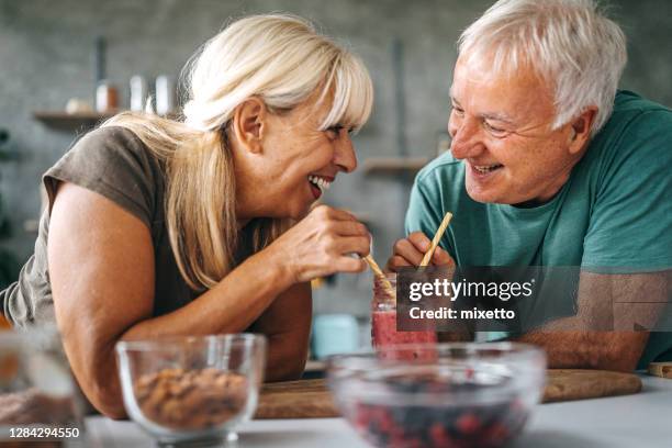 loving couple drinking smoothie in kitchen - straw stock pictures, royalty-free photos & images