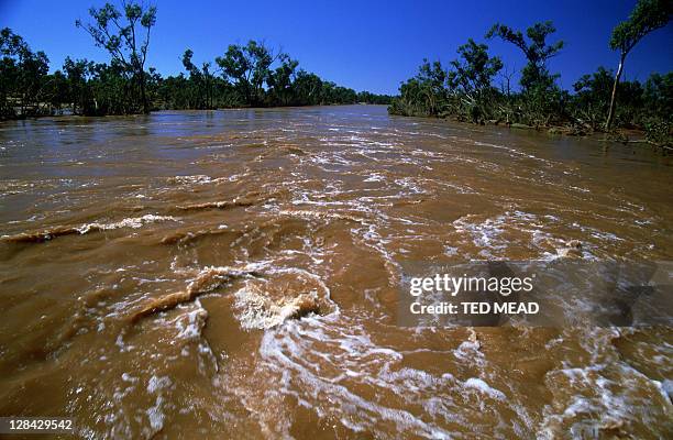 swirling, muddy flood waters of the finke river, northern territory, australia - lodo fotografías e imágenes de stock