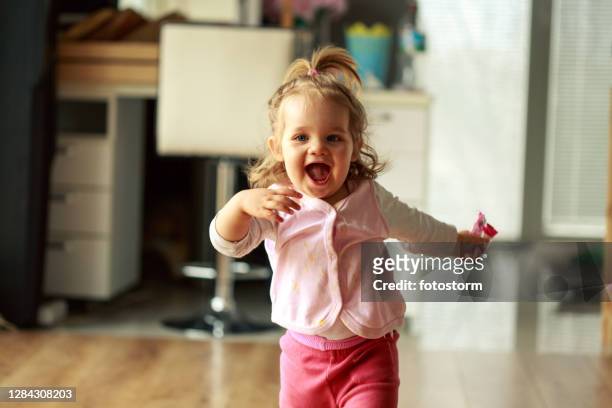 baby girl excitedly running towards someone behind a camera - baby run stock pictures, royalty-free photos & images
