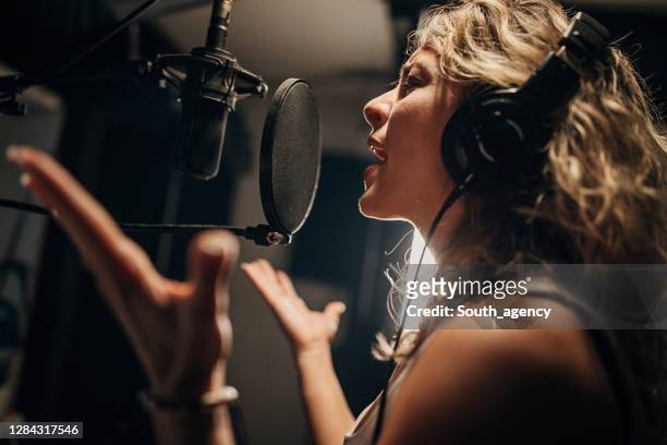female singer recording song in music studio - singer microphone stock pictures, royalty-free photos & images