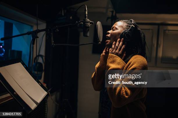 zwarte vrouwelijke singer die in microfoon in opnamestudio zingt - zangeres stockfoto's en -beelden